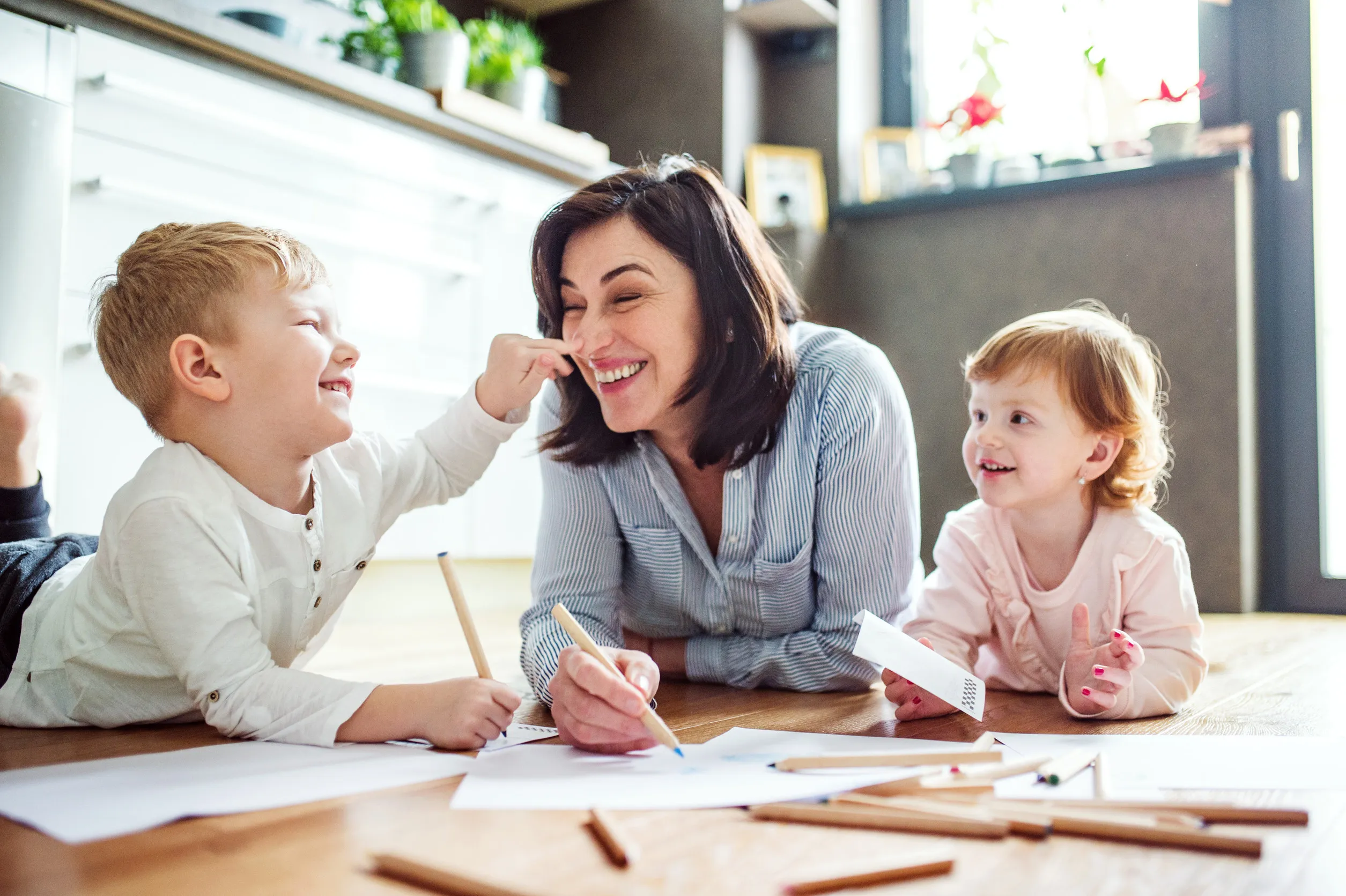 Grandma takes care of the grandchildren while their parents are at work, doing crafts, drawing on paper on floor Grandma takes care of the grandchildren while their parents are at work, doing crafts, drawing on paper on floor
